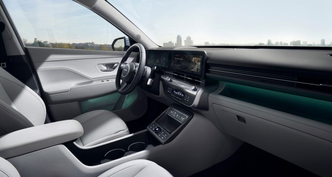 A view of the driver's seat from the passenger seat of The all-new KONA. The driver's door is open, and safety-related messages are displayed on the display.