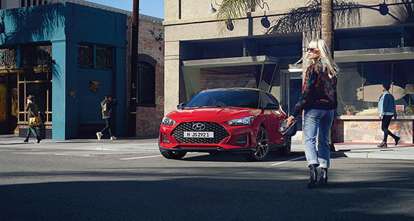 Red veloster next to a woman