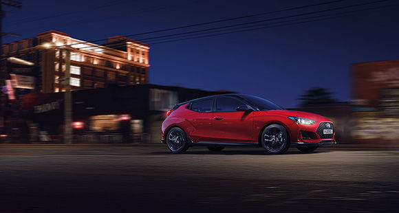 Right side view of red veloster driving on the road