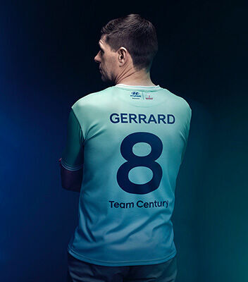 뒷면에 짙은 파란색으로 “제라드”, “8”, “Team Century”라는 문구가 쓰여 있는 Team Century 유니폼을 입은 스티븐 제라드의 모습입니다.