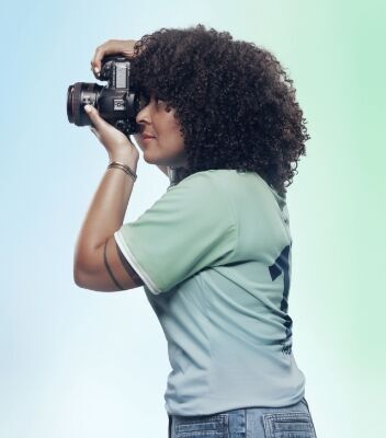 카메라로 사진을 찍고 있는 니키우의 측면 이미지. 현대 로고가 프린트 된 옅은 녹색의 팀 센츄리 유니폼을 입고 있습니다.