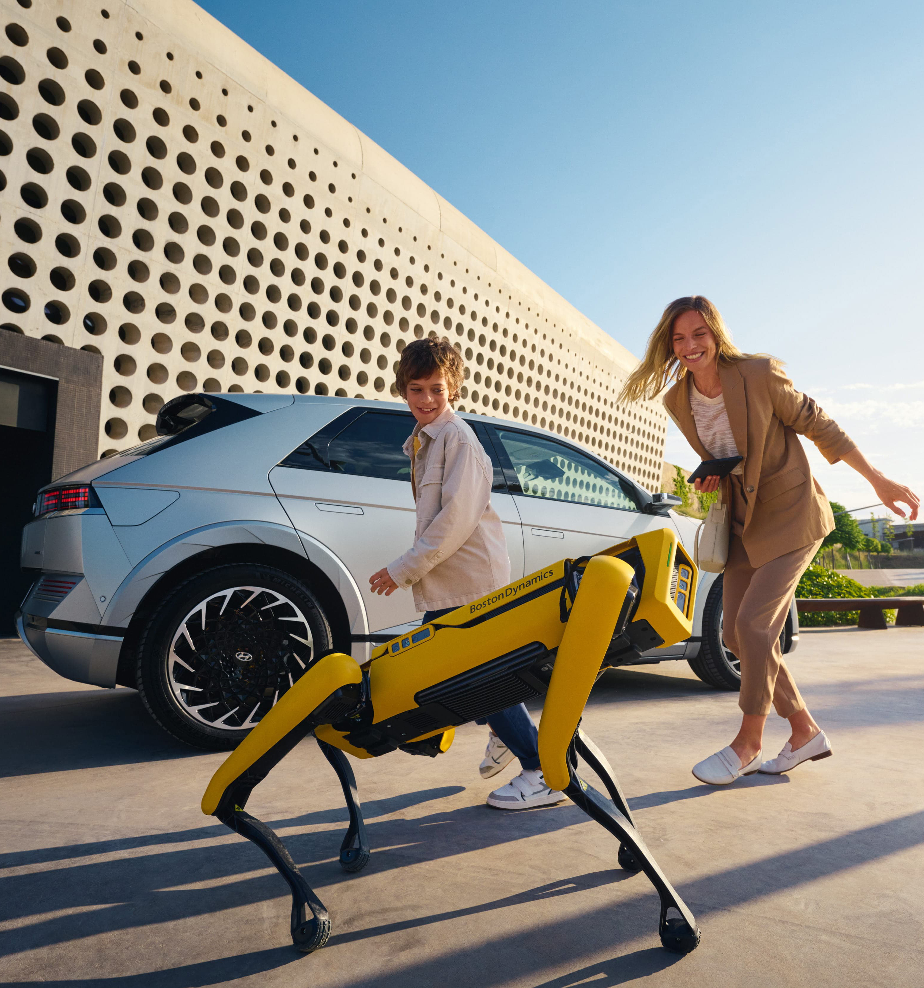 Spot le robot, une mère et son fils à côté de leur véhicule électrique Hyundai IONIQ 5.