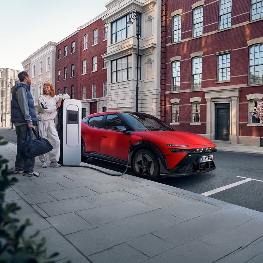 Un homme et une femme en train de discuter à côté d'une borne de recharge sur laquelle est branchée Hyundai IONIQ 3