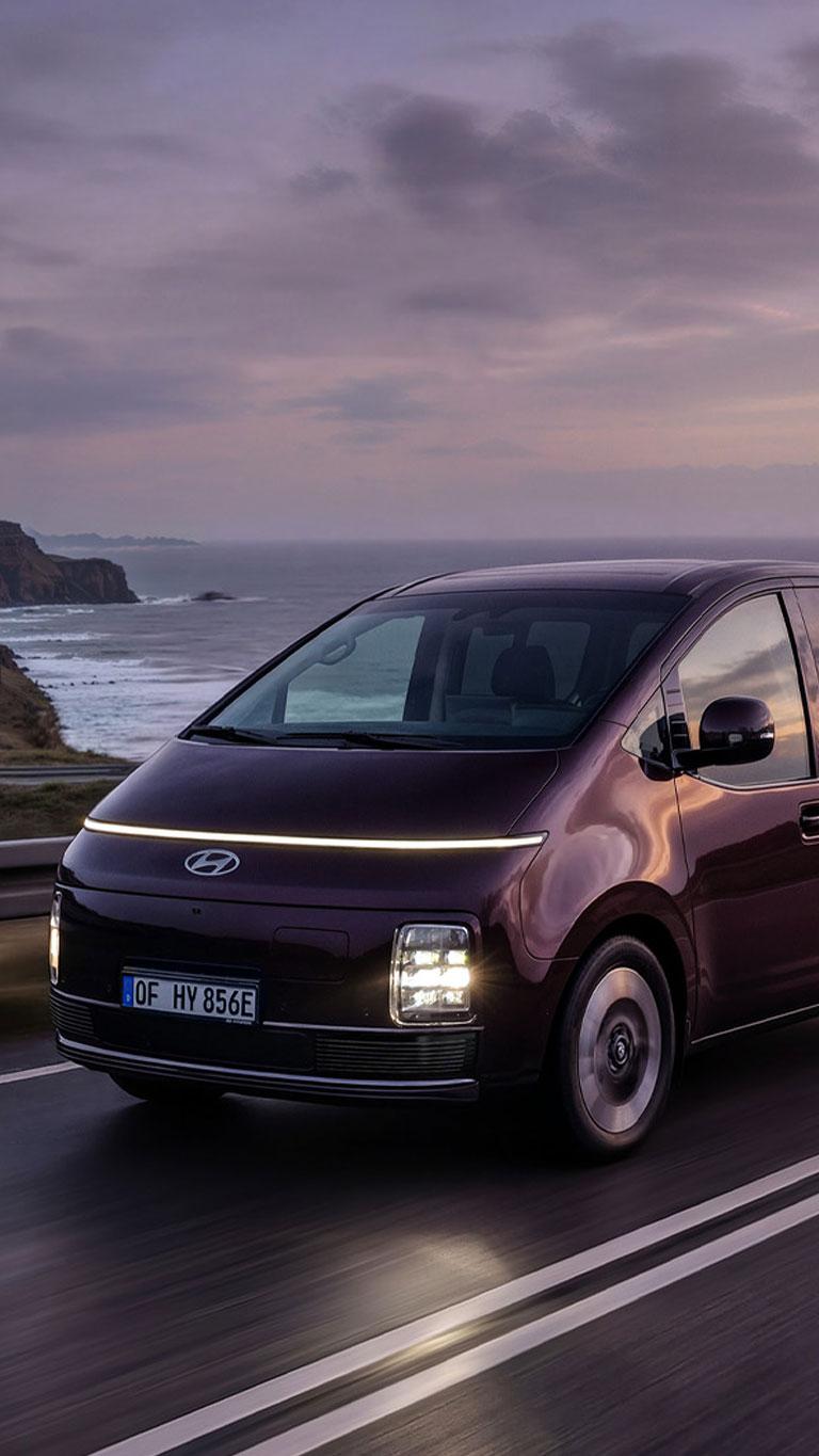 Helt nye STARIA Electric kjørende på en kystvei. Foto. 