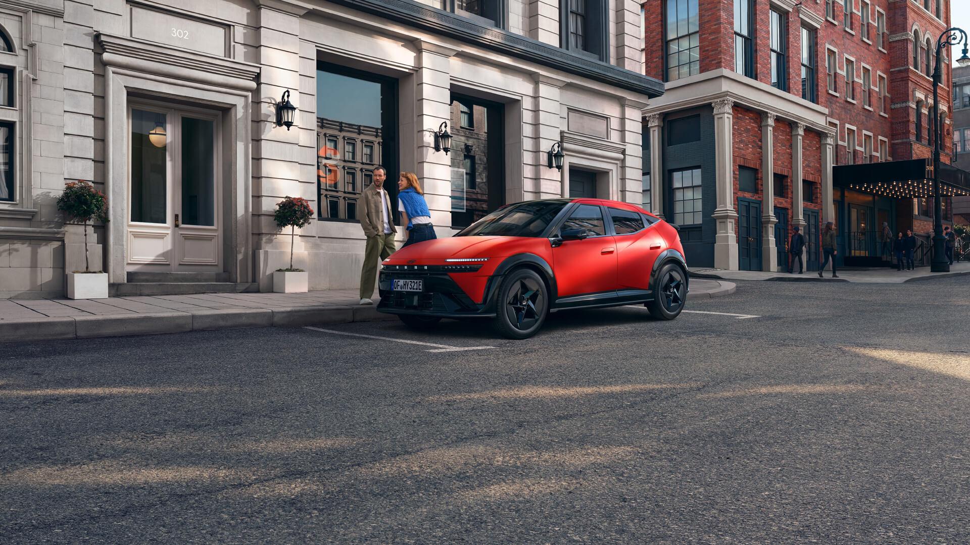 Ein roter Hyundai IONIQ 3, der auf einer Stadtstraße geparkt ist, dargestellt aus einer vorderen Dreiviertelansicht.