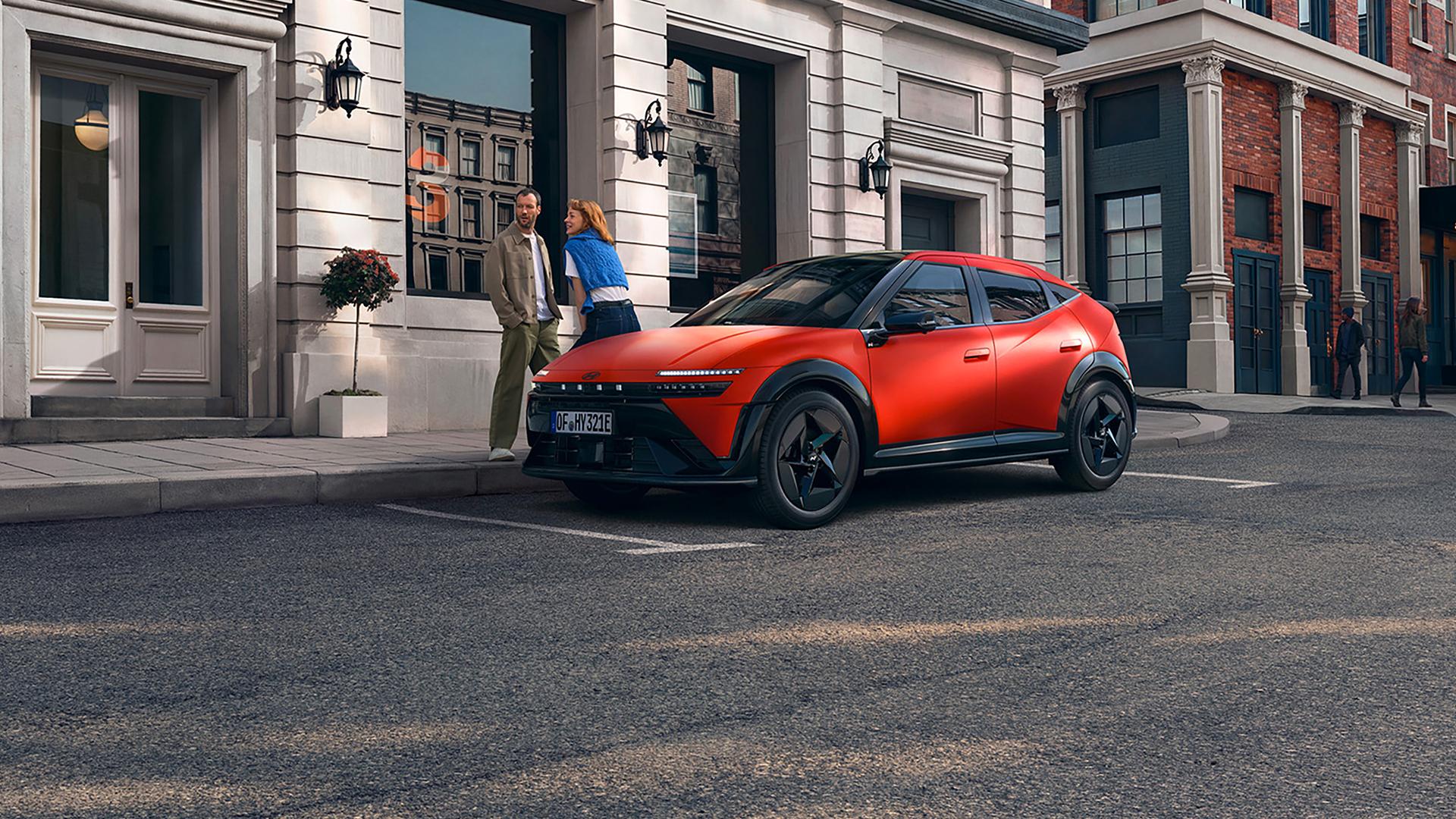 Un homme et une femme parlent devant IONIQ 3 garé dans la rue