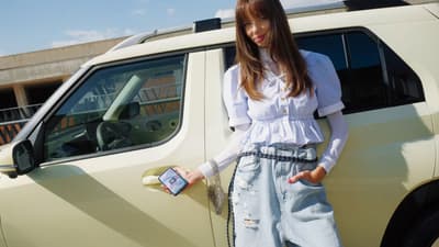 En dame står foran en INSTER med en smarttelefon. Foto.