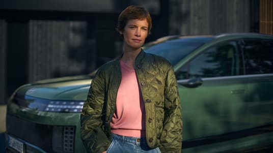 En dame står fpran en IONIQ 9. Foto.