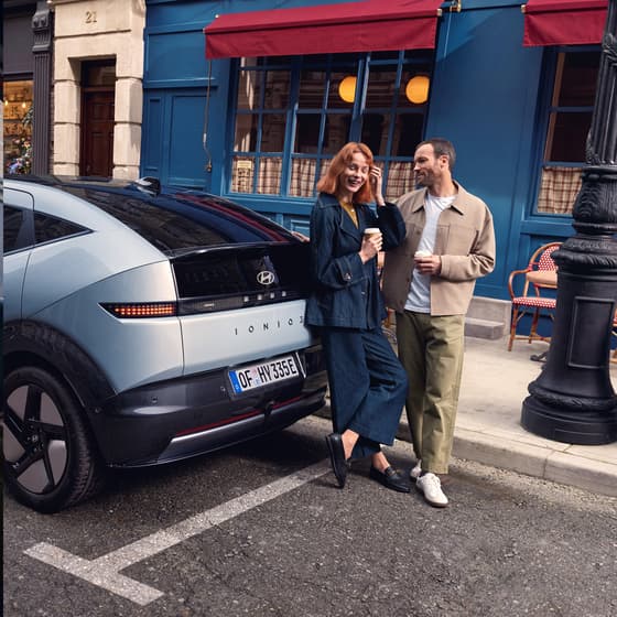 A Hyundai vehicle parked on a city street with two people walking beside it.