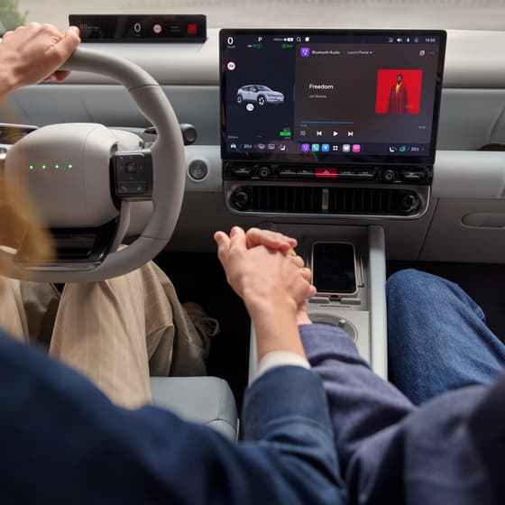 A driver and passenger interacting with the digital displays and controls inside a Hyundai vehicle.