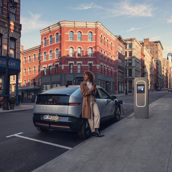 A Hyundai vehicle parked next to a charging station in an urban setting.