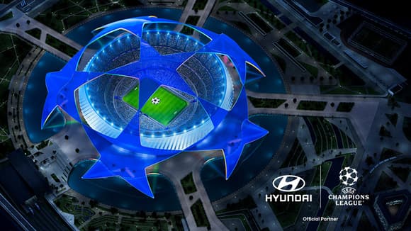 Flygvy över en upplyst fotbollsarena formad som UEFA Champions League-logotypen, med Hyundai- och UEFA Champions League