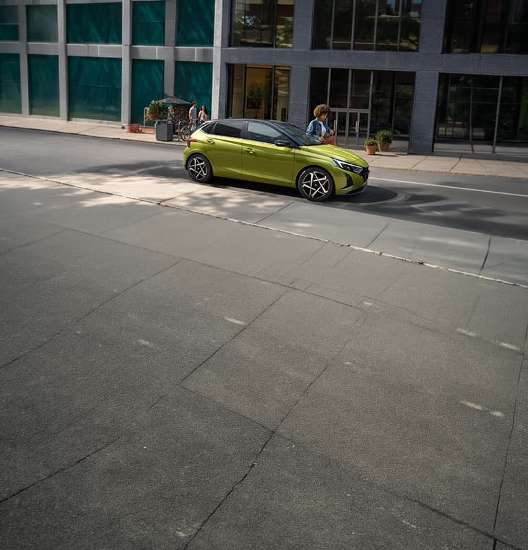 Une jeune femme sortant de sa Hyundai i20 dans une rue passante