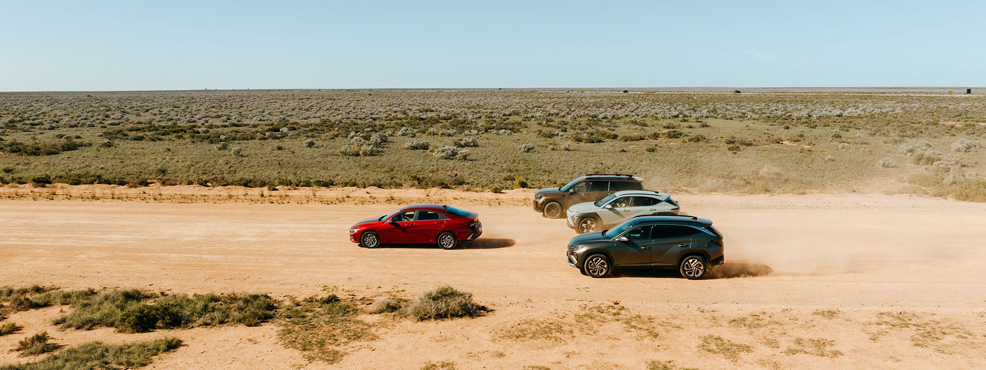 i30 Sedan Hybrid, TUCSON Hybrid, KONA Hybrid, and SANTA FE Hybrid—power through a rugged desert trail, showcasing dynamic performance, dust-kicking agility, and eco-conscious engineering in motion.