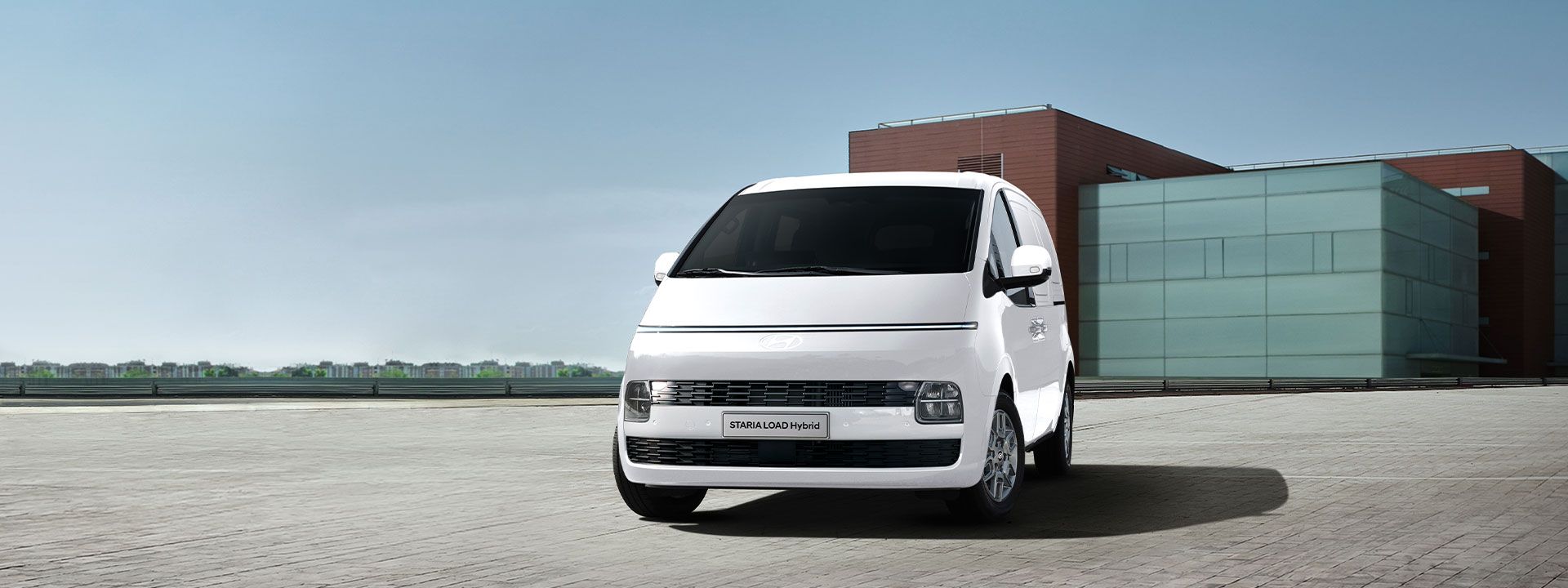 Hyundai STARIA Load Hybrid van showcased in a modern urban setting, highlighting sleek design, spacious cargo capability, and efficient hybrid performance for business fleets.