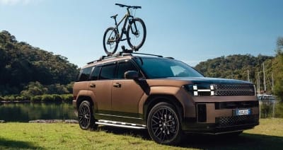 Hyundai Santa Fe Hybrid parked by a scenic lakeside with a bike mounted on the roof, showcasing its modern design, versatility, and adventure-ready capability.