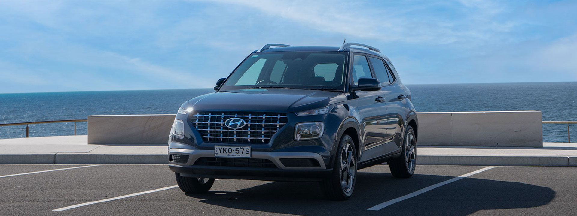 Hyundai VENUE parked by the ocean in Sydney, showcasing contemporary design against a serene coastal backdrop.