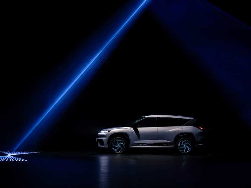 Hyundai ELEXIO electric SUV in a dramatic blue-lit setting, showcasing futuristic design, bold contours, and advanced EV styling.