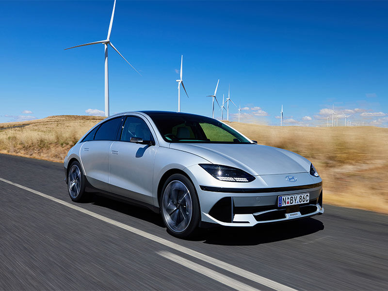 Hyundai  IONIQ 6 electric car is set against a scenic outdoor backdrop filled with windmills