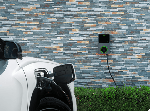 A white Hyundai ELEXIO parked and connected to a wall-mounted home EV charging unit with a glowing green status indicator ring, set against a modern textured slate-tiled wall.