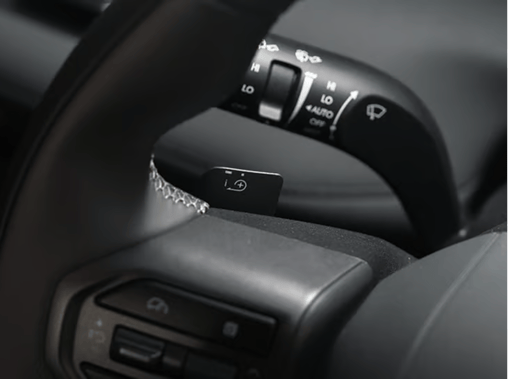 Extreme close-up of the steering wheel column in a Hyundai ELEXIO, focusing on the steering wheel paddle shifter marked with the i-Pedal symbol for regenerative braking control.