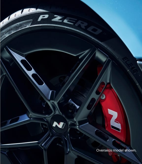 A close-up of a Hyundai Ioniq 6 N's black alloy wheel, red brake caliper, and Pirelli P Zero tire