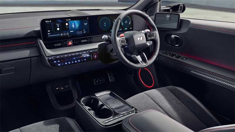 Interior view of the Hyundai IONIQ 5 N Line, highlighting the sporty steering wheel with red stitching and red accents throughout the cabin