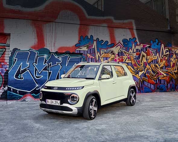 Hyundai Inster compact electric SUV with roof rack and cargo setup, showcasing urban adventure styling and modern design in an outdoor driveway setting