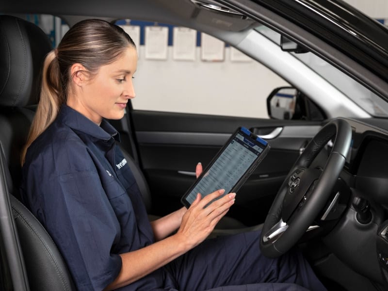 Technician using a tablet for vehicle diagnostics, highlighting Hyundai’s tech-driven servicing.