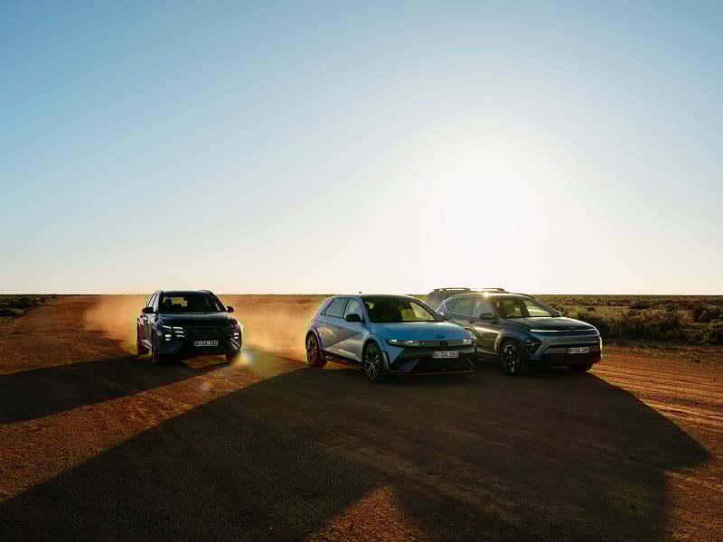 Hyundai TUCSON Hybrid, KONA Hybrid, SANTA FE Hybrid, IONIQ 5 N power through rugged terrain at sunset, spotlighting durability and a 7-year unlimited km warranty.