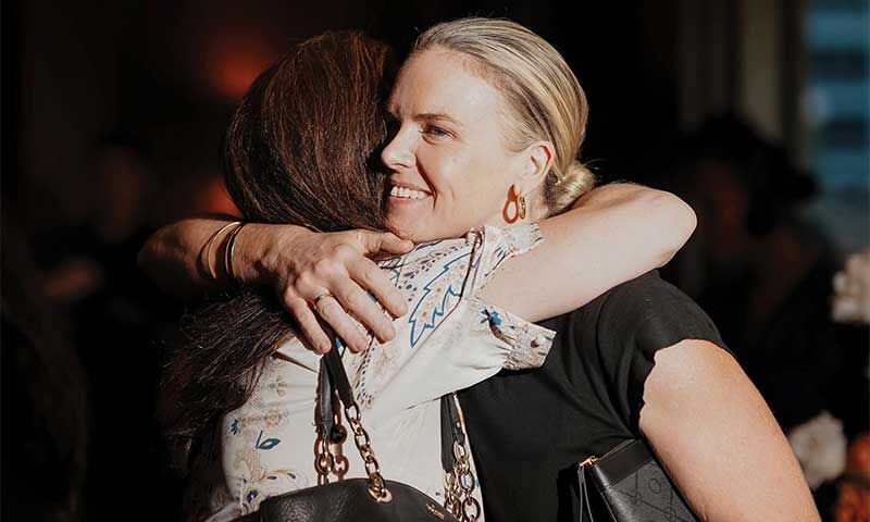 Two women embracing warmly at a social event
