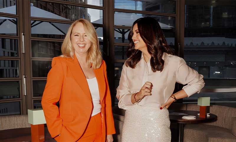 Two women smiling in an office event setting