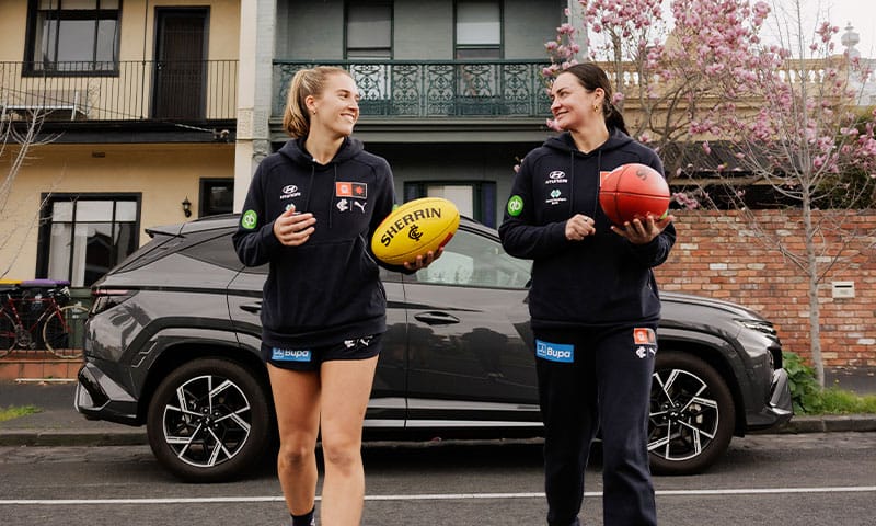 Hyundai TUCSON parked on a suburban street alongside Carlton Football Club athletes, highlighting Hyundai sponsorship, active lifestyles and contemporary SUV styling.