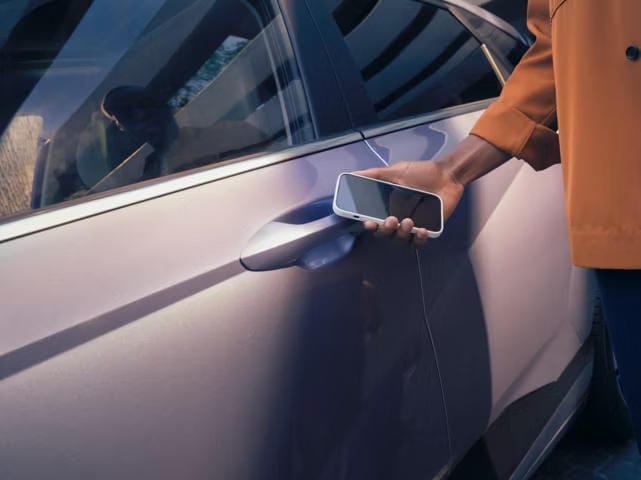 Una persona utiliza un smartphone y Hyundai Digital Key para desbloquear la puerta del conductor de un Hyundai KONA.