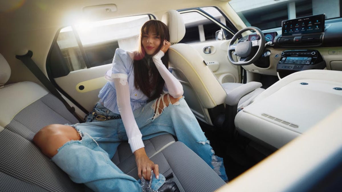 Una mujer se relaja en el interior del nuevo coche eléctrico compacto Hyundai INSTER, mostrando su interior espacioso y moderno.