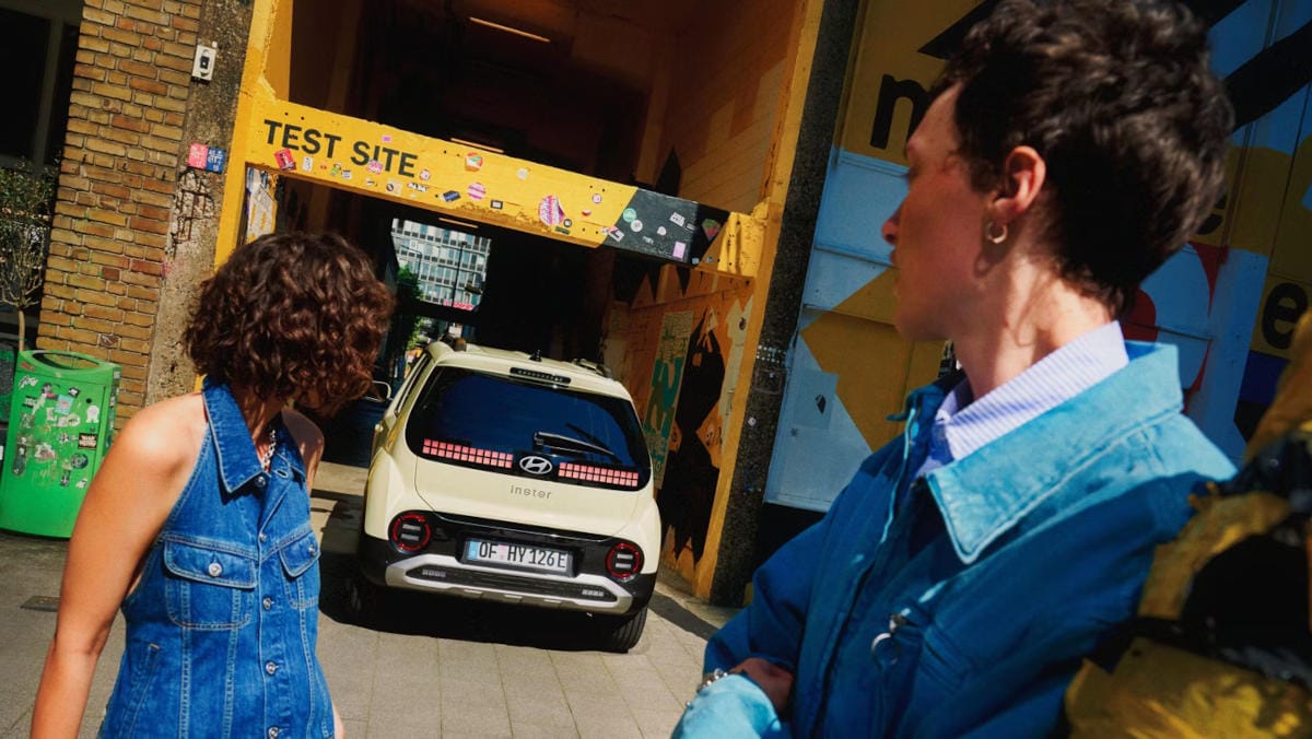 Una mujer mira el portón trasero del nuevo coche eléctrico compacto Hyundai INSTER.