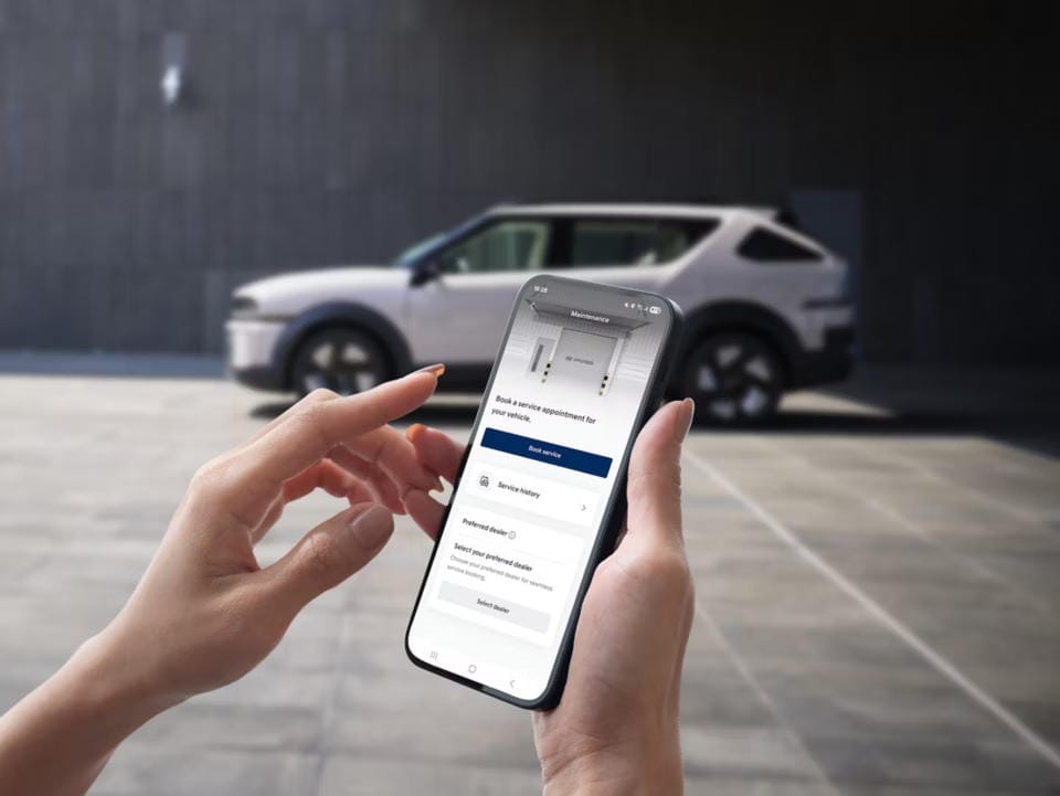 Hyundai NEXO en el fondo. Una persona está revisando la aplicación myHyundai.