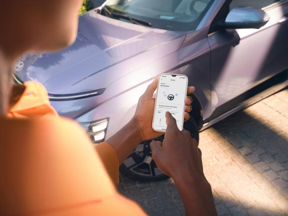 Perspectiva por encima del hombro, una persona está revisando la distancia total recorrida este mes en la aplicación.