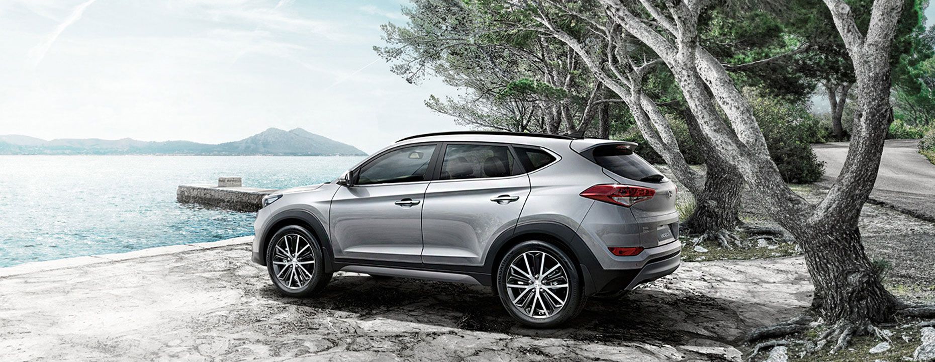 A brown accent parked on parking lot and right of the picture has a white building