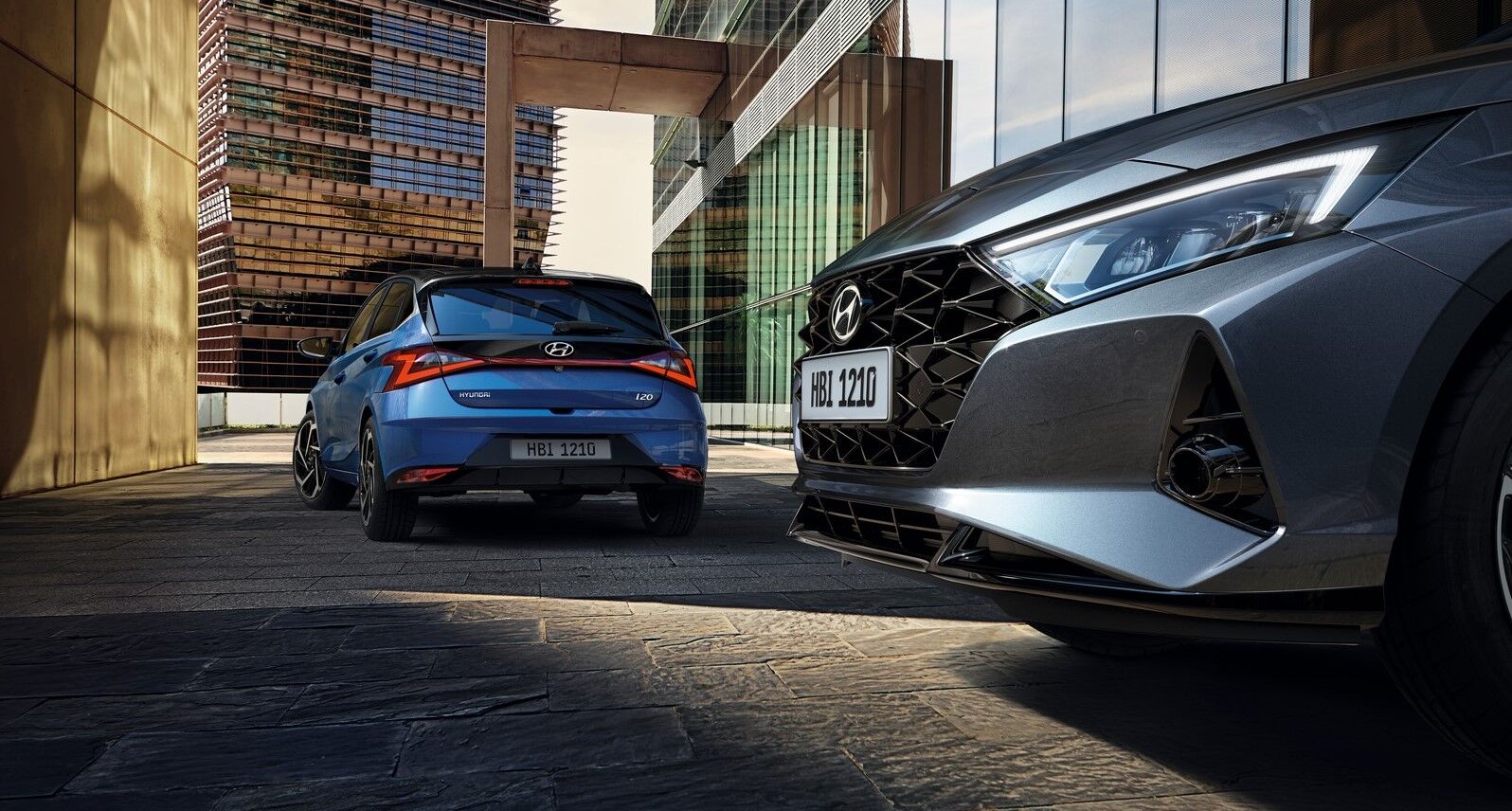 Side front view in front and side rear view of silver i20 at the back