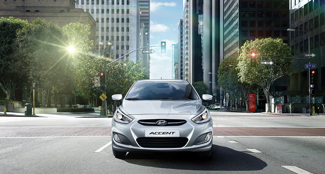 Front view of gray Accent driving in the middle of the city street