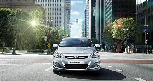 Front view of gray Accent driving in the middle of the city street