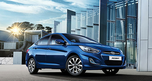 Side front view of blue Accent parked in front of the building