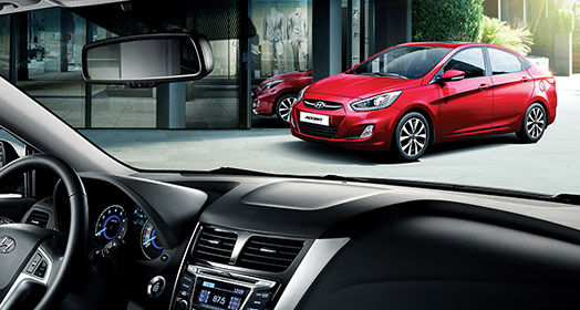 Side-front view of red Accent parked in front of the building from the passenger's viewpoint through front windshield