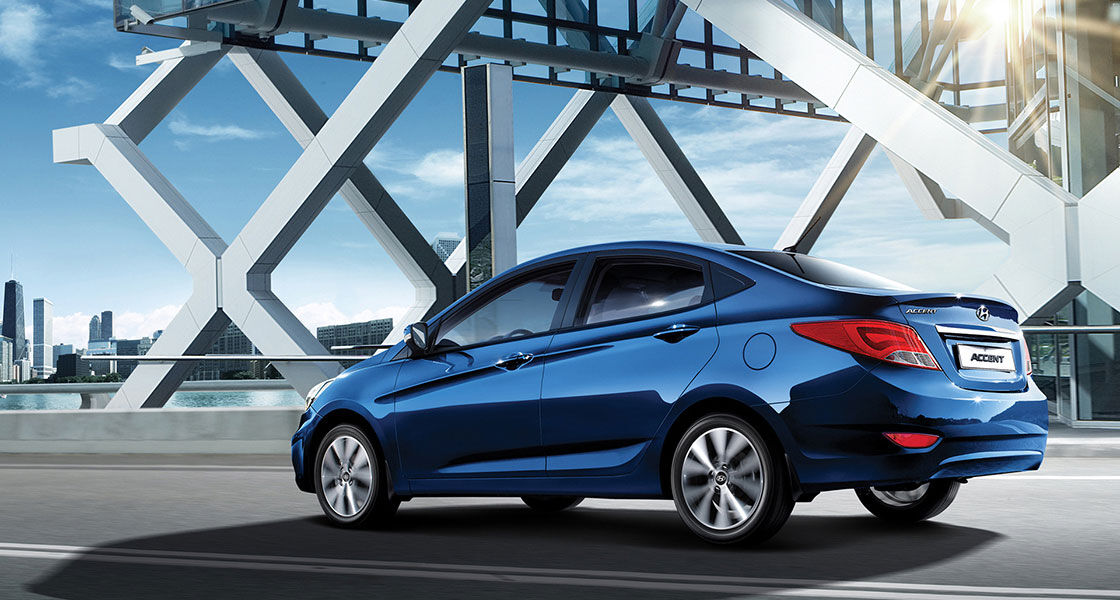 Side-rear view of blue Accent driving on the road with sunlight at the back