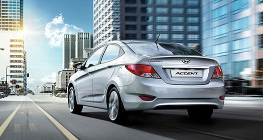 Side-rear view of silver Accent driving through the towers in the city
