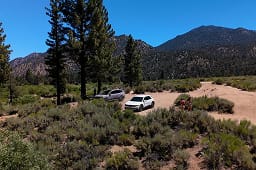 Two IONIQ vehicles parked in a mountainous woodland landscape as two young adventurers explore nearby.