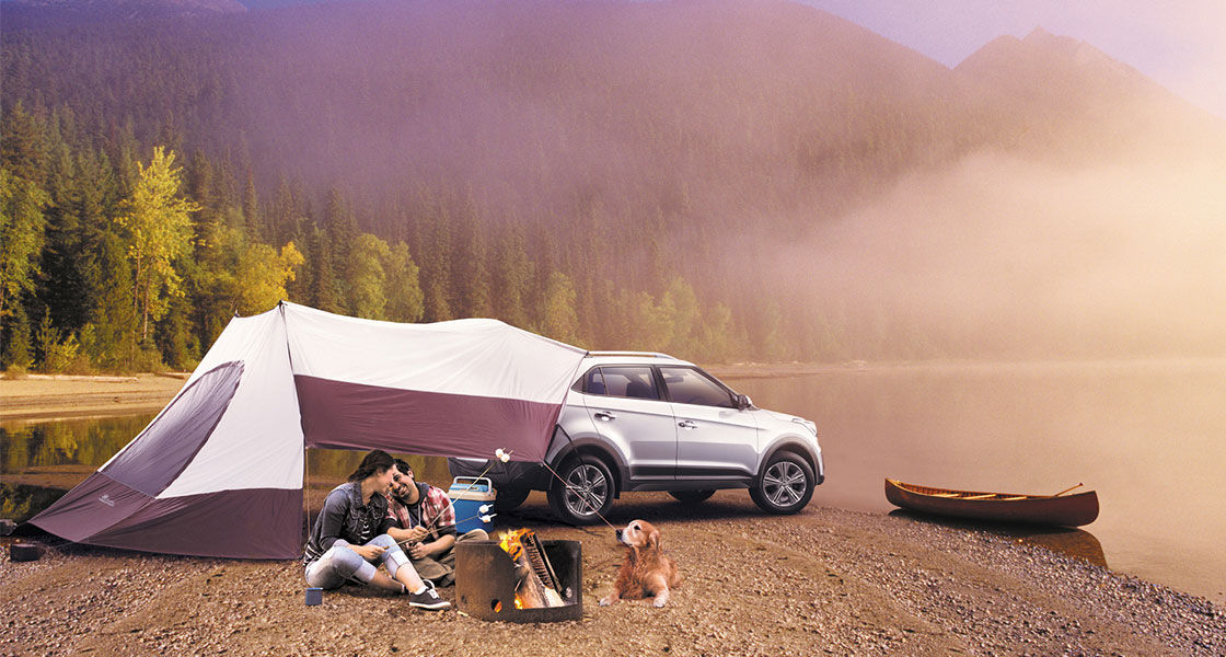 Family enjoying camping with a dog at lake with white Creta and tent