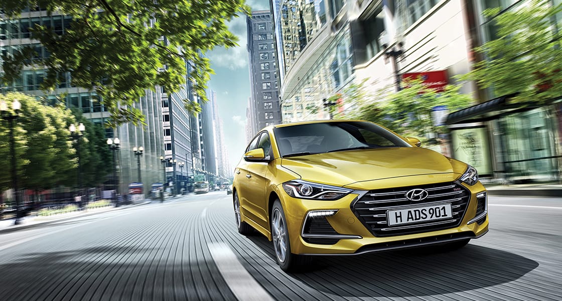 Right side front view of yellow Elantra Sport driving on the street