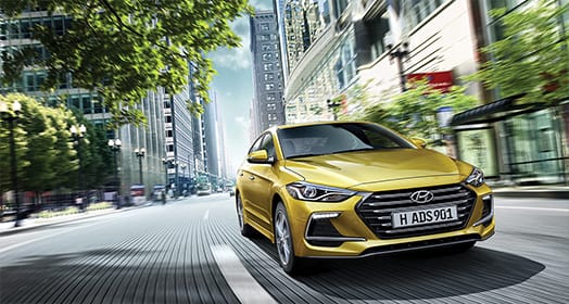 Right side front view of yellow Elantra Sport driving on the street
